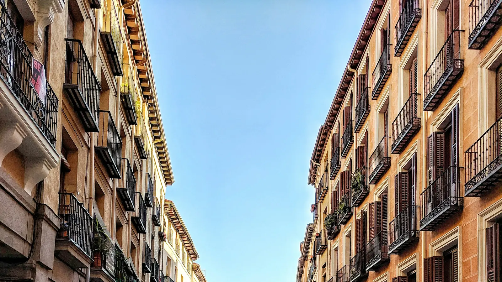 Facades of residential apartment buildings in central Madrid, with a rental sign on one balcony